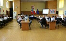 Trwa sesja Rady Powiatu Włoszczowskiego. Radni siedzą przy stołach.